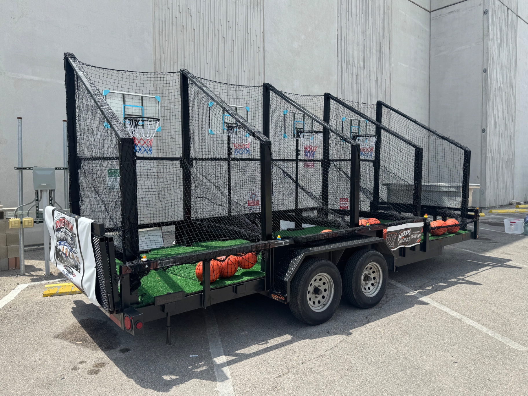 Three-quarter view of the Hoops on Wheels trailer showing the full netted rig and the branded banner