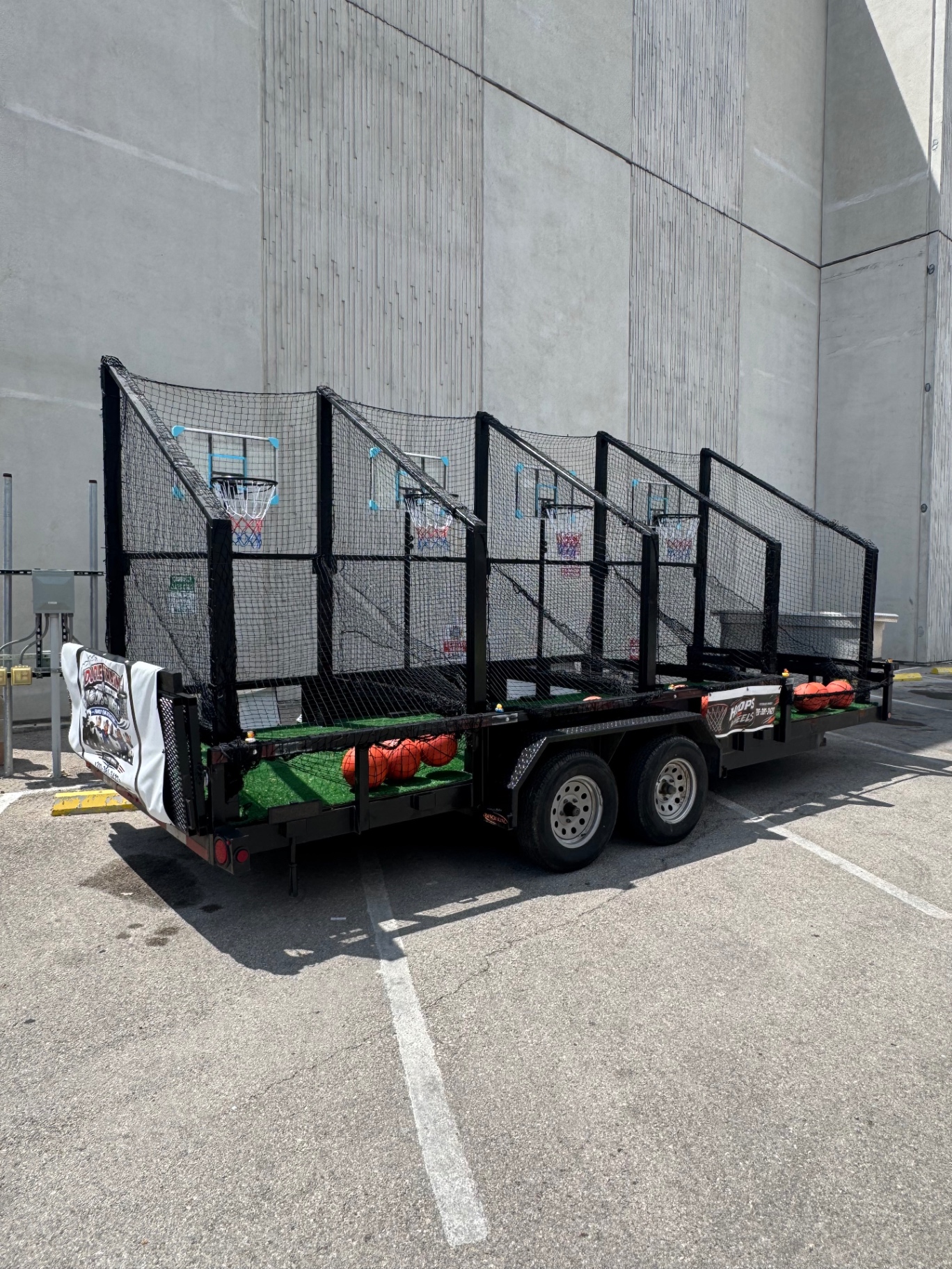 The Hoops on Wheels trailer parked outdoors with the Doodle Train and Hoops on Wheels banner draped over the side rail
