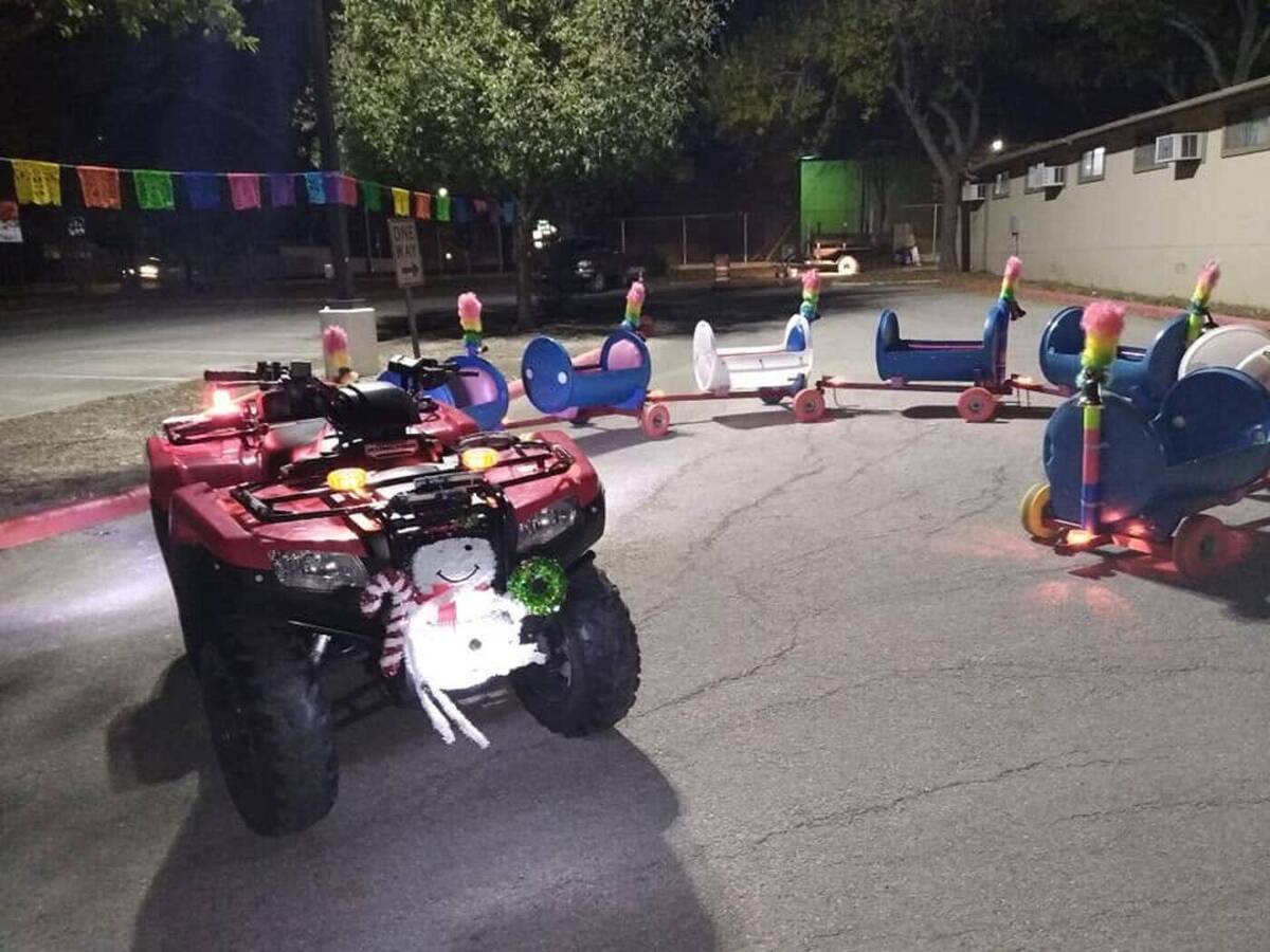The real Doodle Train cars lit behind the towing vehicle at an evening event